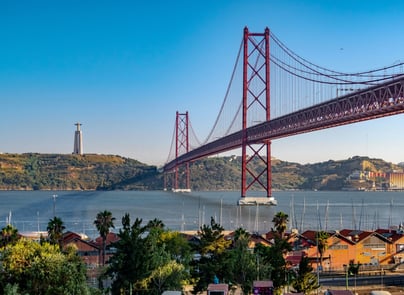 View of the 25 de Abril Bridge in Lisbon with the Cristo Rei statue in the background and the Tagus River in the foreground — one of the city’s most iconic landmarks connecting Lisbon and Almada.