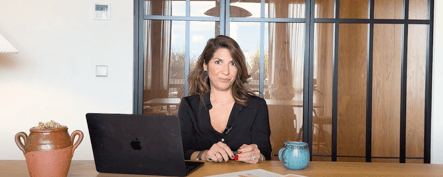 Businesswoman working in a modern office with a laptop, decorative pottery, and natural light, representing a professional and inspiring workspace in Portugal.