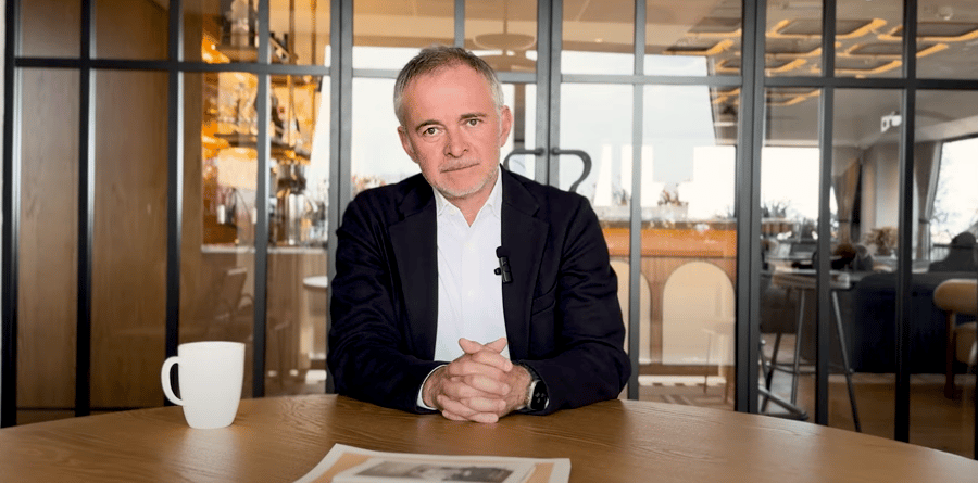 Man in a modern corporate setting, seated at a table with a coffee mug and papers, representing leadership and business in Portugal.