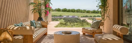 Sunlit terrace with luxury furniture and garden view in Comporta, Portugal. Elegant outdoor space from Ando Living project, blending comfort, design, and tranquility.