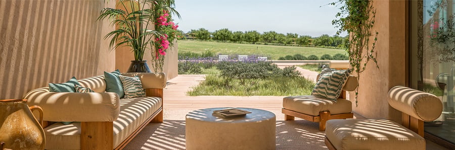 Sunlit terrace with luxury furniture and garden view in Comporta, Portugal. Elegant outdoor space from Ando Living project, blending comfort, design, and tranquility.