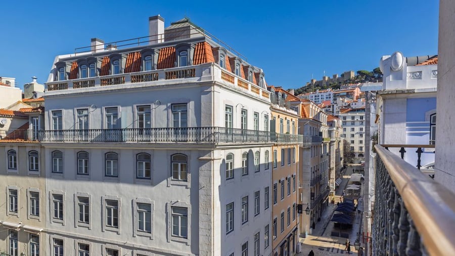 Urban view of Lisbon with historic buildings and São Jorge Castle in the background on a sunny day.