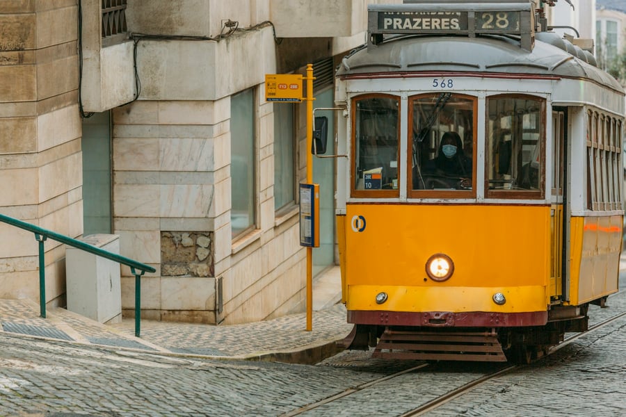 Tram 28 in Lisbon climbing a traditional cobblestone street. The iconic yellow tram symbolizes the charm and heritage of the Portuguese capital.