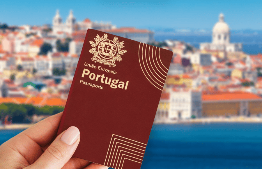 Hand holding a Portuguese passport with Lisbon in the background