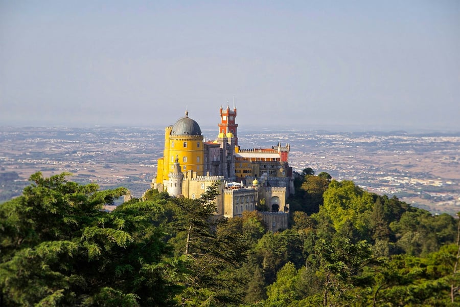 Pena Palace in Sintra, Portugal, surrounded by lush greenery with panoramic views over the region. One of the most iconic examples of Portuguese romantic architecture and a UNESCO World Heritage Site.