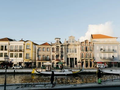 View of Aveiro canals with traditional moliceiro boats and colorful Art Nouveau facades reflected on the water.