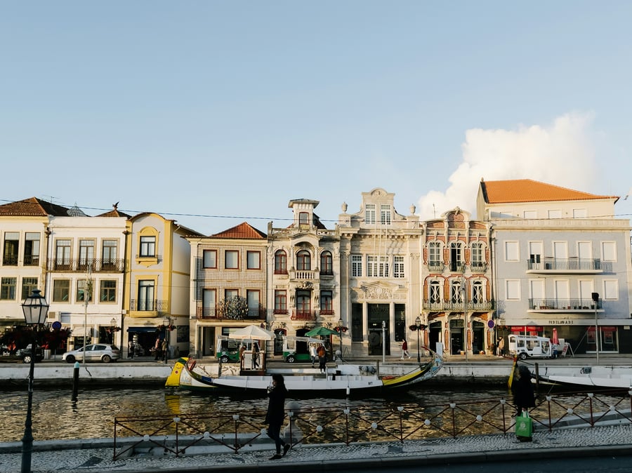 View of Aveiro canals with traditional moliceiro boats and colorful Art Nouveau facades reflected on the water.