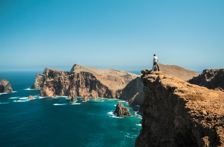 Man standing on cliff at Ponta de São Lourenço, Madeira, Portugal, overlooking the Atlantic Ocean and the island’s dramatic rock formations.