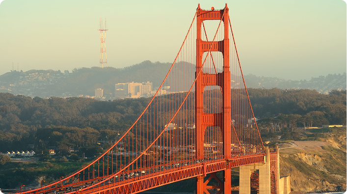 Golden Gate Bridge in San Francisco at sunset with a sailboat cruising through the bay waters.