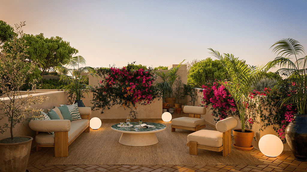 Modern terrace with comfortable sofas, low table, and tropical flowers at sunset, showcasing lifestyle linked to Golden Visa investments in Portugal