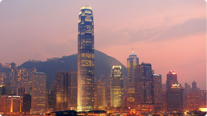 Panoramic view of illuminated skyscrapers at sunset in Victoria Harbour, Hong Kong.